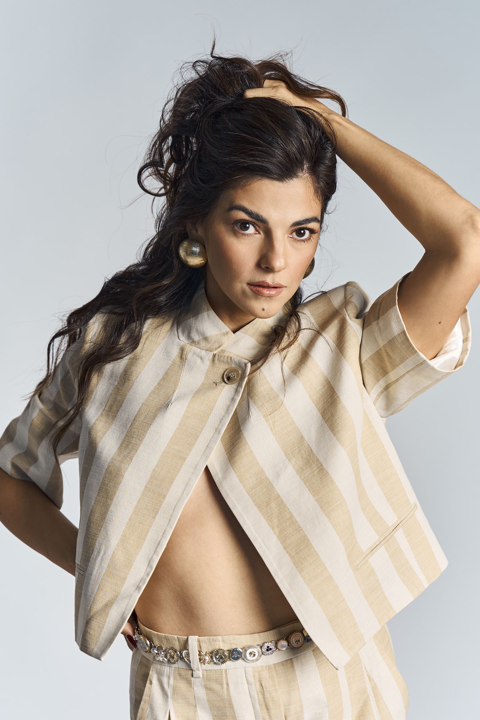 Striped linen co-ord, one hand lifting the ponytail, bright even studio lighting.