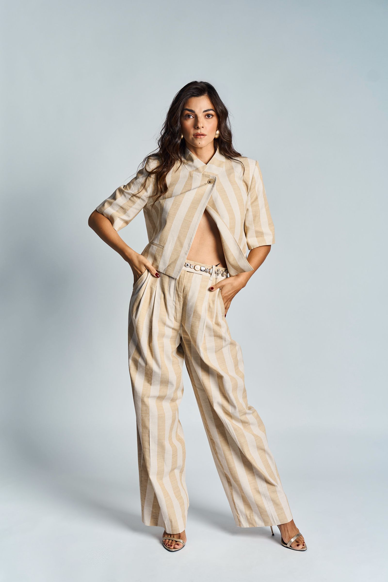 Striped short-sleeved jacket and matching trousers, hands in pockets, full length under studio light.